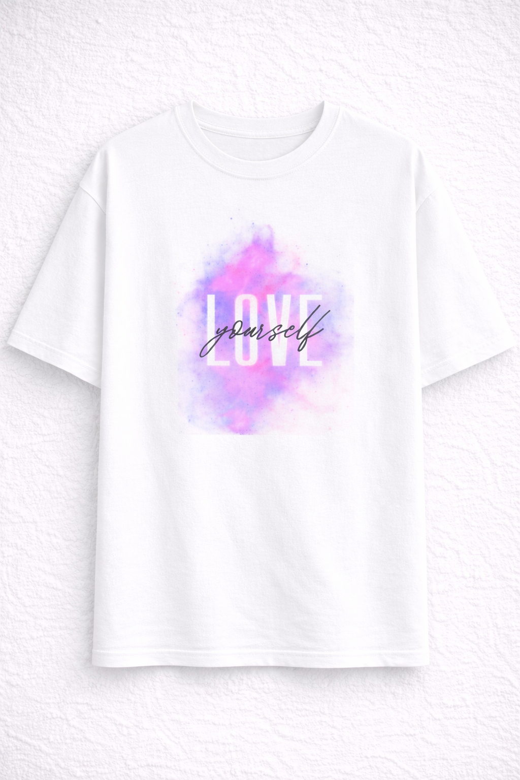 White t-shirt with 'love yourself' text and watercolor design on a light gray background
